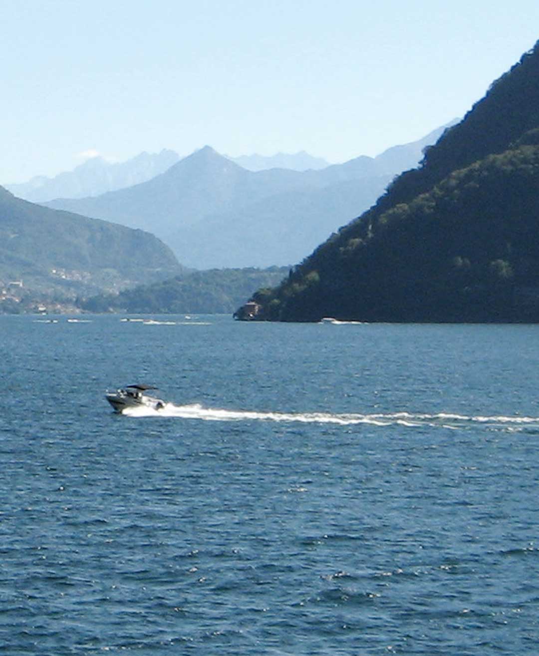 Barca in navigazione che lascia la scia sulle acque del lago di Como